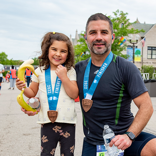 father and small daughter post race with medal and snacks father and small daughter post race with medal and snacks